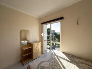 Quarto com janela de porta para a varanda e armário de madeira.
