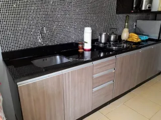 Cozinha moderna com armários de madeira e bancadas escuras.