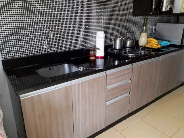 Cozinha moderna com armários de madeira e bancadas escuras.