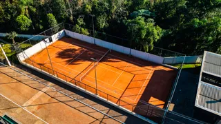 Vista aérea de uma quadra esportiva ao ar livre cercada por vegetação densa.