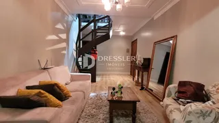 Sala de estar com sofá e escadaria de madeira.