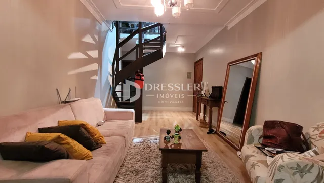 Sala de estar com sofá e escadaria de madeira.