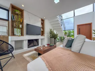 Sala de estar moderna com lareira e grandes janelas em um imóvel no Brasil.