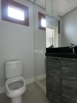 Foto de um banheiro com vaso sanitário e espelho refletindo o ambiente.