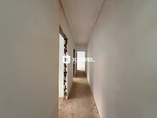 Corredor interno com paredes brancas e piso claro.