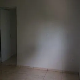 Vista interna de um cômodo com paredes brancas e piso de cerâmica.