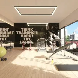 Sala de ginástica com equipamentos de treino e piso de madeira.