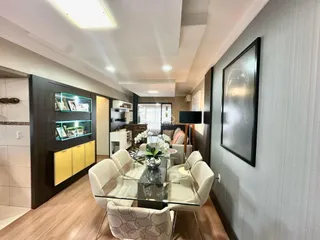Sala de estar moderna com piso de madeira e decoração clara.