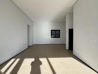 Vista interna de um ambiente com paredes brancas e piso claro.