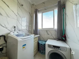 Interior de um ambiente com revestimento de azulejo branco e máquinas de lavar roupa.