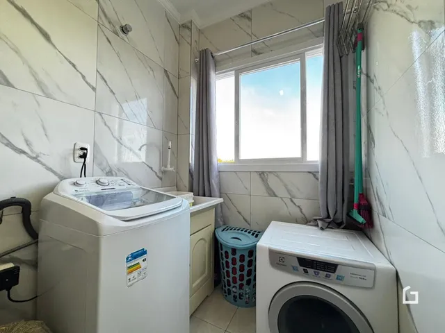 Interior de um ambiente com revestimento de azulejo branco e máquinas de lavar roupa.