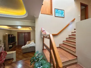 Vista de um corredor com escadaria de madeira em uma residência.