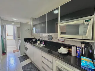 Vista da cozinha moderna com armários brancos e bancadas escuras.
