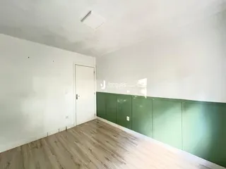 Ambiente interno com piso de madeira clara e painel verde na parede.