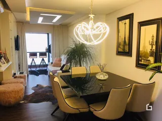 Sala de estar com piso de madeira escura e luminária de cristal.