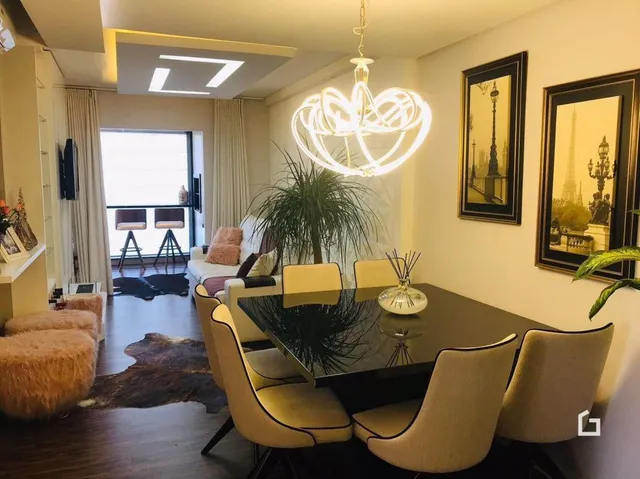 Sala de estar com piso de madeira escura e luminária de cristal.