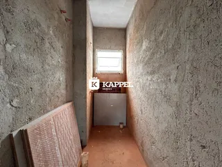 Foto de um corredor interno com paredes de concreto e uma janela no final.