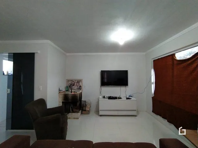 Sala de estar branca com televisão montada na parede.