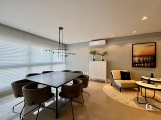 Ambiente interno de uma sala de jantar e estar com grande janela.