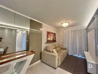 Sala de estar com sofá e cortinas claras em um imóvel no Brasil.