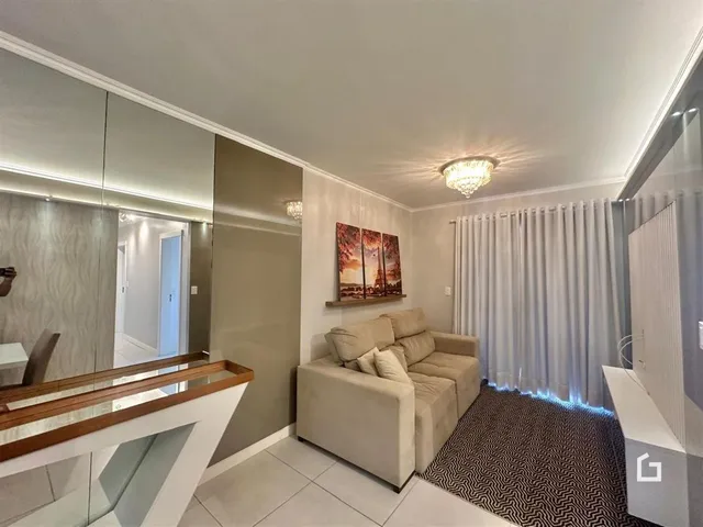 Sala de estar com sofá e cortinas claras em um imóvel no Brasil.