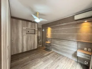 Foto de um quarto com armários em madeira e piso de madeira.
