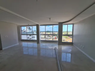 Uma sala ampla com grandes janelas que oferecem uma vista da paisagem urbana.