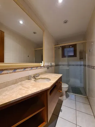 Foto de um banheiro com bancada de mármore e box de vidro.