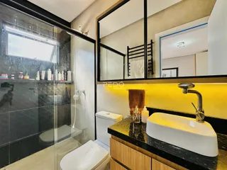 Banheiro moderno com box de vidro e bancada de granito.