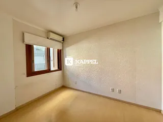 Foto interna de um cômodo com piso de madeira e janela.