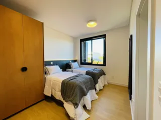 Quarto com duas camas de solteiro e armário de madeira.