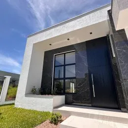 Fachada moderna de uma residência com revestimento branco e detalhes escuros.