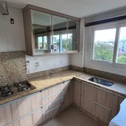 Foto de uma cozinha com armários e bancada em um imóvel.