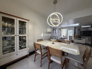 Sala de jantar clara com mesa de madeira e armários brancos.