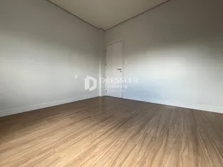 Foto de um cômodo vazio com piso de madeira clara e paredes brancas.