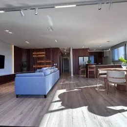 Sala de estar com sofá azul e piso de madeira.
