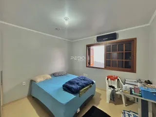 Quarto com cama azul e janela de madeira em um imóvel no Brasil.