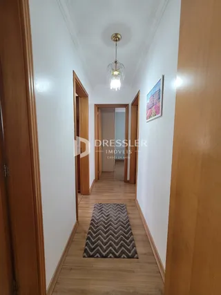 Corredor interno de uma residência com piso de madeira.