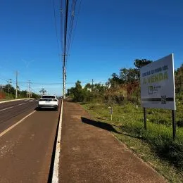 Vista de uma estrada com vegetação ao fundo.