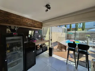 A sala de estar e cozinha se abrem para uma área externa com piscina.