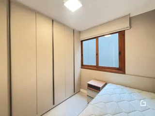 Quarto com armários embutidos e janela de madeira.