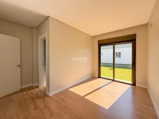 Interior de uma sala com piso de madeira e porta de vidro que dá para um jardim.