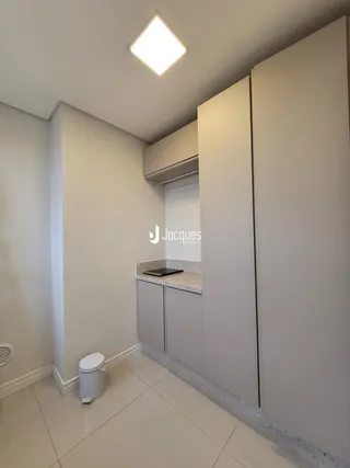 Interior de uma cozinha moderna com armários brancos e piso claro.