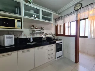 Foto de uma cozinha interna com armários brancos e bancadas escuras.