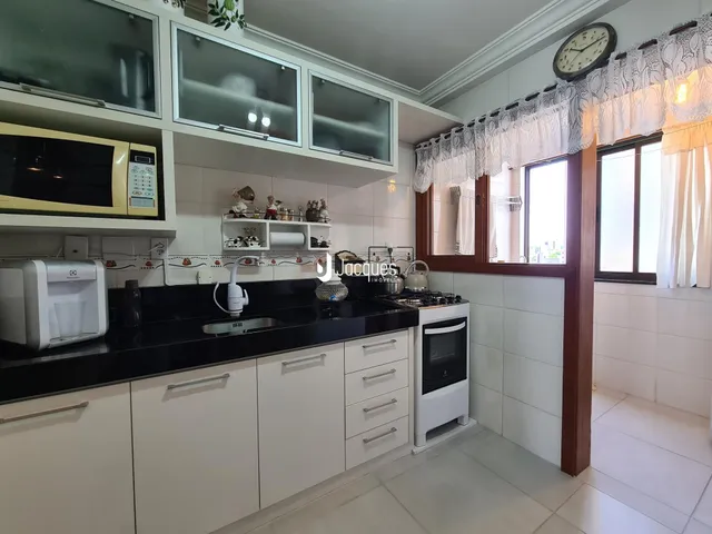 Foto de uma cozinha interna com armários brancos e bancadas escuras.