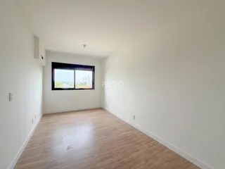 Ambiente interno de uma sala com piso de madeira clara e janela.