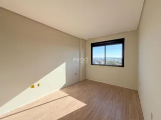 Interior de uma sala com piso de madeira e grande janela com vista.