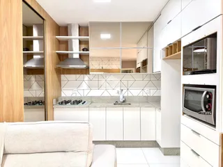 Cozinha moderna com armários brancos e revestimento de azulejos.