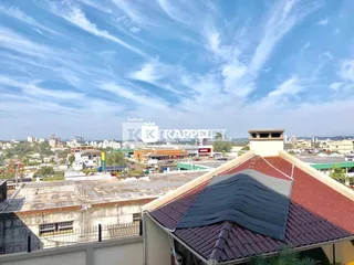 Vista da fachada de um imóvel em Lajeado, Brasil, mostrando a estrutura do telhado e a paisagem urbana ao fundo.