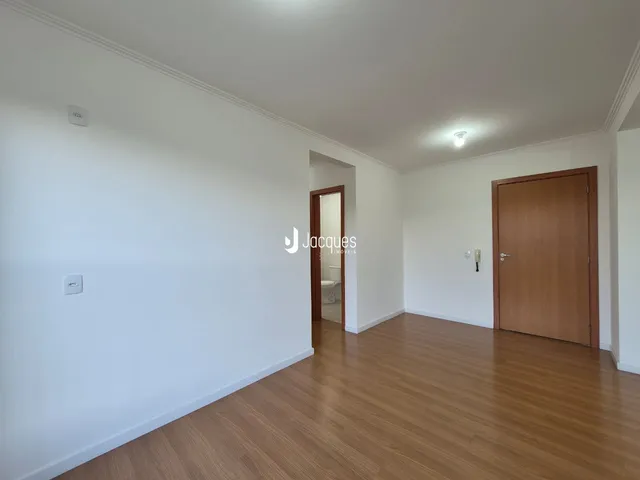 Vista interna de um ambiente com piso de madeira clara e paredes brancas.